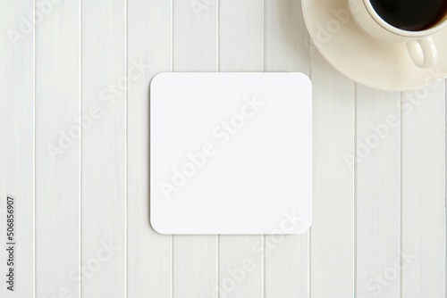 White blank square coaster mockup for design presentation on white wooden table.