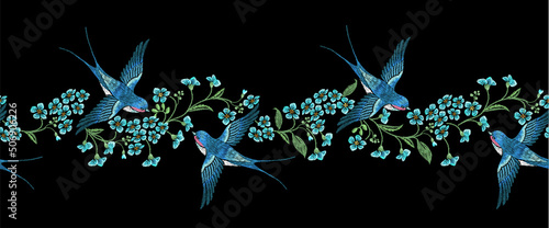 Embroidery horizontal seamless border with blue forget-me-not flowers and swallows on a black background