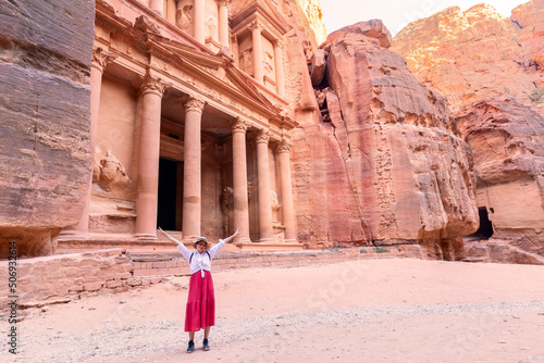 Rear view of beautiful young woman standing with open arms in front of the treasure of petra, Jordan