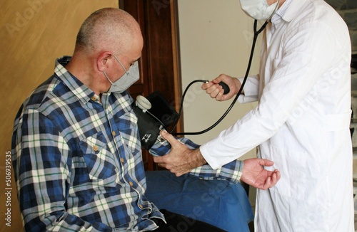 Médico accionando tensiómetro para medir presión arterial en paciente adulto