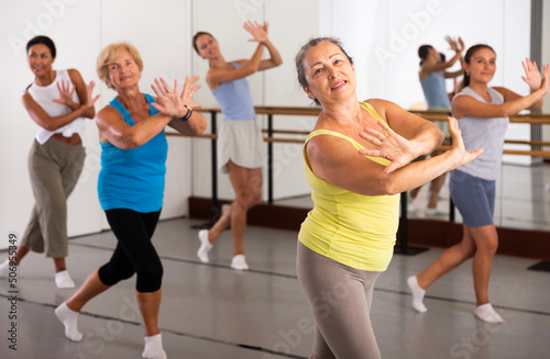 Group of various aged women dancing modern dance in studio.