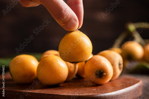 hand holding golden loquat fruit on table