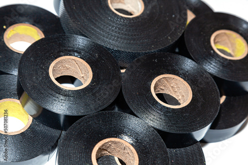 Several skeins of black electrical tape stacked next to each other on a white background, close-up.
