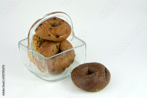 Variety of cinnamon raisin, sesame seed, and pumpernickel bagels inside glass basket