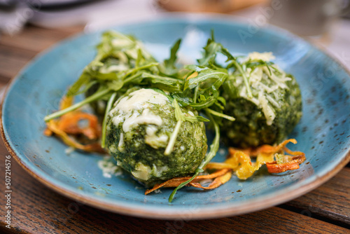 Close up of spinach dumplings with melted butter topped with mountain cheese and vegetables. 