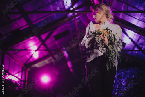 Dziewczyna w koszuli z bukietem kwiatów w opuszczonej szklarni