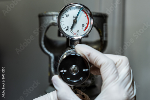 Close up of a hand in gloves adjusting a barometer of a nitrogen cylinder or compressed air