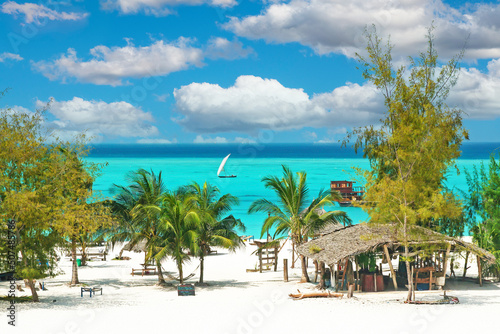 Beautiful tranquil empty bright white paradise sand beach, sun beds, palm trees, bamboo hut bar, turquoise water - Paje, Zanzibar