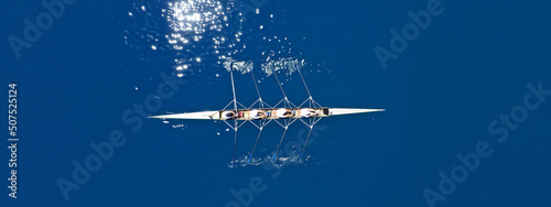 Aerial drone top ultra wide panoramic view of sport canoe rowing synchronous team of athletes competing in deep blue sea