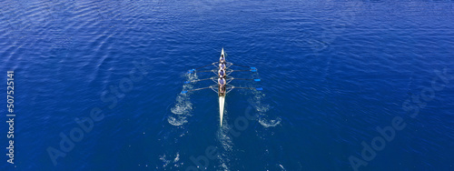 Aerial drone top ultra wide panoramic view of sport canoe rowing synchronous team of athletes competing in deep blue sea