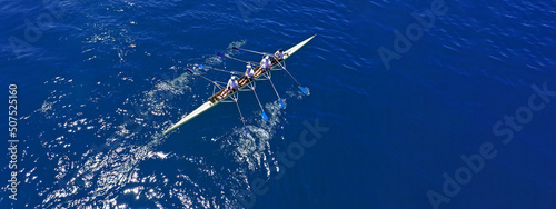 Aerial drone top ultra wide panoramic view of sport canoe rowing synchronous team of athletes competing in deep blue sea