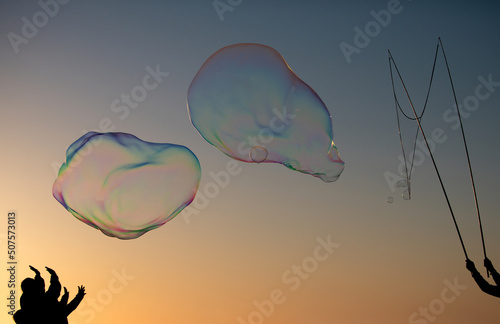Big soap bubbles in sunset. Giant soap bubble. Flying soap bubbles on sky blue background at sunset.
