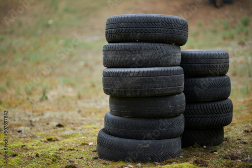 Tires are stacked on a background of green grass. car tires