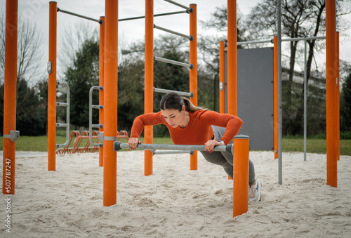 Strong fit sporty woman doing push ups at city park outdoor gym. Fitness calisthenics workout.