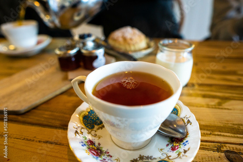 Cup of tea in bone china teacup with scones in the background