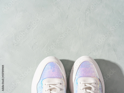 White pastel sneakers with sequins on geometric podiums on turquoise