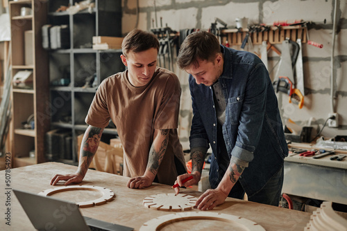 Portrait of two artisan shop owners designing wooden furniture in workshop interior