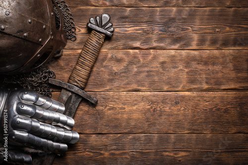 Ancient knight sword and armor on the wooden table flat lay background with copy space.