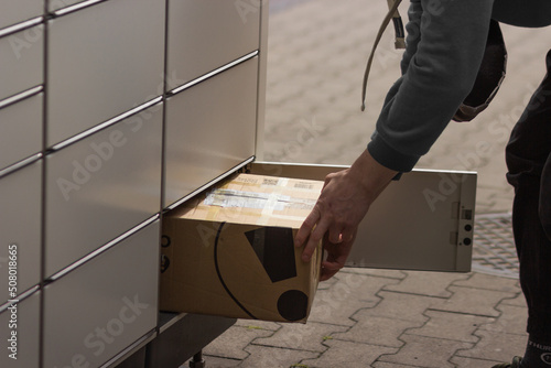 Man receives or sends a box from shopping locker in postal terminal. E-commerce shipping and delivery service.