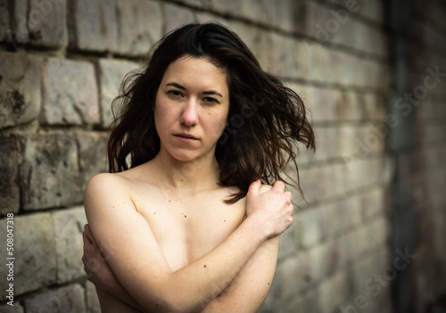 27 year old white woman with bare upperbody, protecting her chest with folded arms