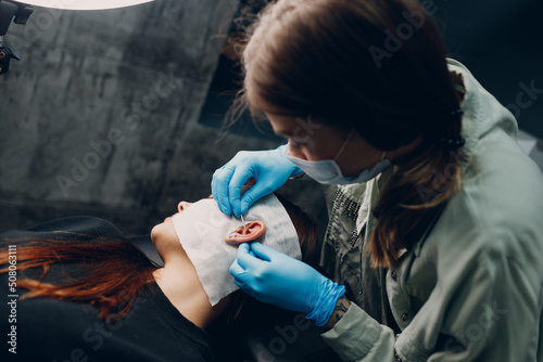 Young woman doing piercing at beauty studio salon