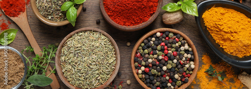 Different herbs and spices on wooden table, flat lay. Banner design