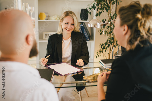 Happy couple having conversation with real estate agent in the office.