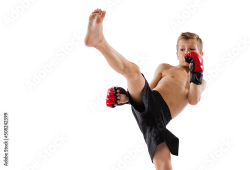 Beginner athlete, kid in sports shots and gloves practicing thai boxing on white studio background. Sport, education, action, motion concept.