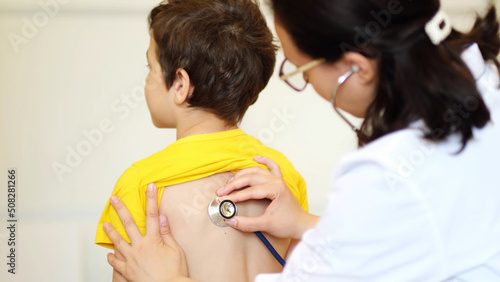 doctor listens to breath of little boy through stethoscope. Pediatrician with stethoscope listening to a lungs in child with bronchitis and cough