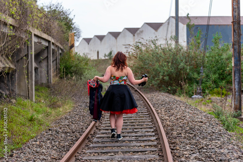 Femme marchant de dos sur des rails de chemin de fer abandonnées