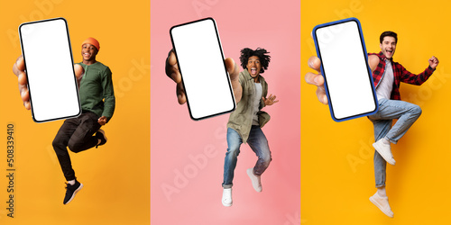 Three happy multiracial millennial guys showing smartphones with empty screen