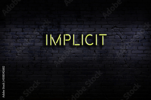 Neon sign. Word implicit against brick wall. Night view