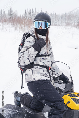 Woman driving snowmobile in winter mountain landscape