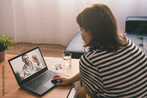 Woman sitting on a sofa and talking with a doctor online using laptop. Telemedicine concept.