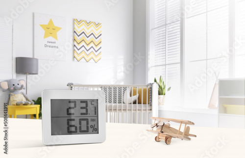 Digital hygrometer with thermometer on white table in children's room. Optimal humidity level for kids