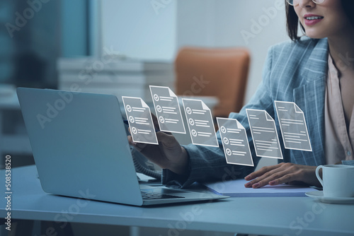 Young secretary with laptop and digital files on virtual screen in office