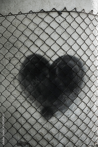 metal mesh fence defense black painted heart. isolated on white column background. Idea, concept of security, protection, guard, safeguard, escort, custody of love. toxic relationship, gaslighting