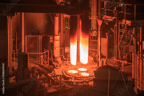 Hot red graphite electrodes in steel mill workshop.