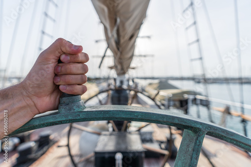 Left hand squeezing ship wheel with blurred background