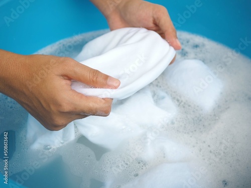 Woman hands washing white clothes in sink. closeup photo, blurred.