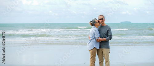  Asian Senior couple walking on the beach enjoy life at sunrise