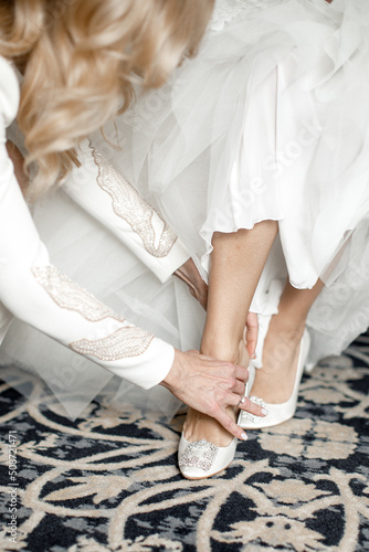 Bridesmaid helping the bride to put on her shoes