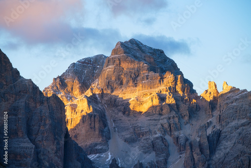 High rocks during sunset. Dolomite Alps, Italy. Mountains and cloudy skies. View of mountains and cliffs. Natural mountain scenery. Photography as a background for travel.
