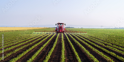 Tractor spraying soybean field at spring