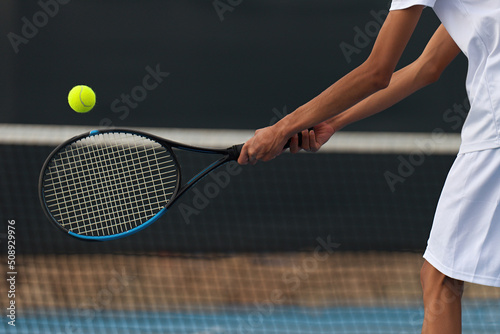 Male tennis player hitting backhand by net on the tennis court