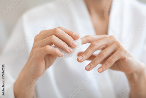 Woman hand removing nail polish with white cotton pad