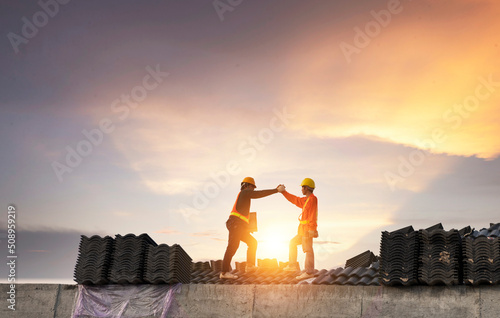 A team of construction workers in work clothes installed new roofing equipment. roofing tools, electric drill, and use it on new wood roofs with metal sheets.