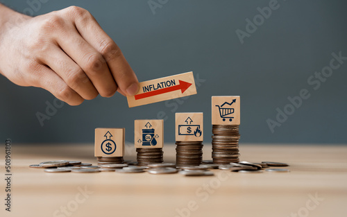 Hand putting wooden cube and inflation word a on coins in idea for FED consider interest rate hike, world economics, and inflation control, US dollar inflation