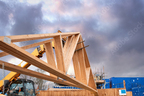 Heavy machinery shifting roof trusses on new residential housing development construction site