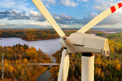 Renewable energy generator. Wind power generator close-up. Fragment of wind generator with blades. Windmill in autumn forest. Landscape with wind turbine. Offshore power plant in taiga.